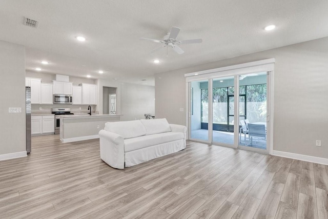 living room with ceiling fan, sink, and light hardwood / wood-style flooring