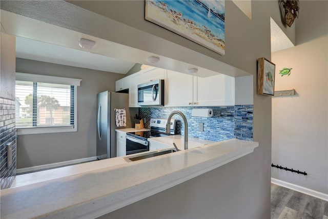 5725 Pelican Pointe Dr Unit 4, Sebastian, FL 32958 - kitchen featuring appliances with stainless steel finishes, light countertops, decorative backsplash, white cabinetry, and wood finished floors