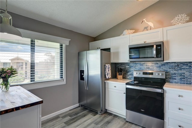 5725 Pelican Pointe Dr Unit 4, Sebastian, FL 32958 - kitchen with stainless steel appliances, decorative backsplash, vaulted ceiling, light wood-style flooring, and white cabinetry