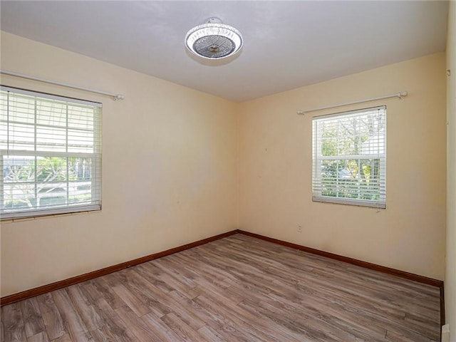 spare room with baseboards and wood finished floors