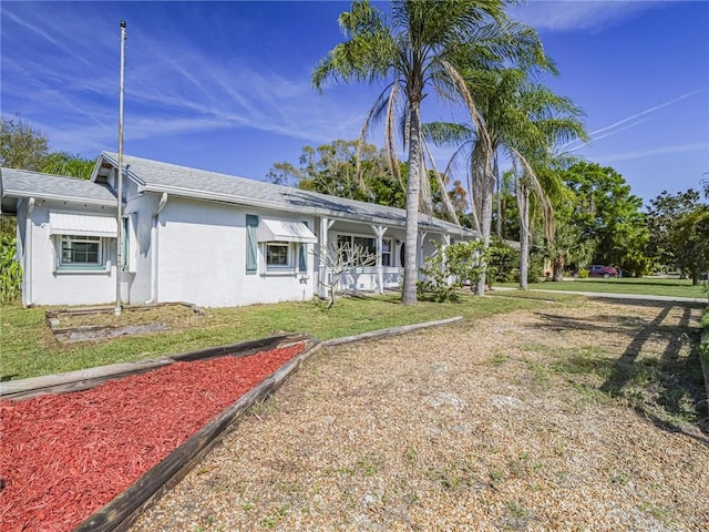 back of property with roof with shingles, a lawn, and stucco siding