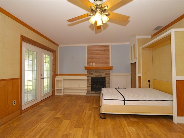 bedroom with visible vents, wainscoting, light wood-style flooring, access to exterior, and crown molding