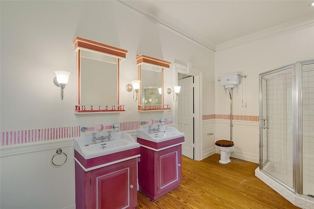 201 Sundial Ct, Vero Beach, FL 32963 - bathroom featuring a shower stall, ornamental molding, wood finished floors, two vanities, and a wainscoted wall