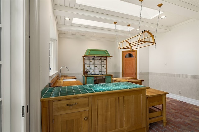 kitchen featuring tile countertops, pendant lighting, sink, and beamed ceiling