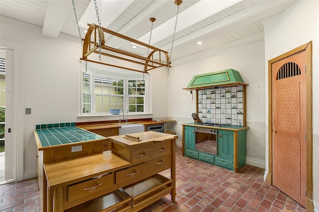 kitchen with butcher block counters, sink, green cabinets, and beam ceiling