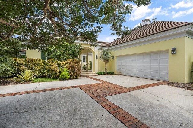 201 Sundial Ct, Vero Beach, FL 32963 - view of front facade with stucco siding, driveway, a chimney, a tiled roof, and an attached garage