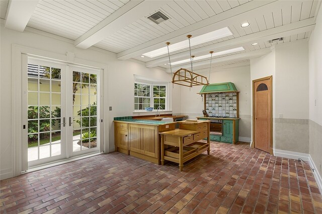 kitchen with beamed ceiling, kitchen peninsula, decorative light fixtures, and french doors