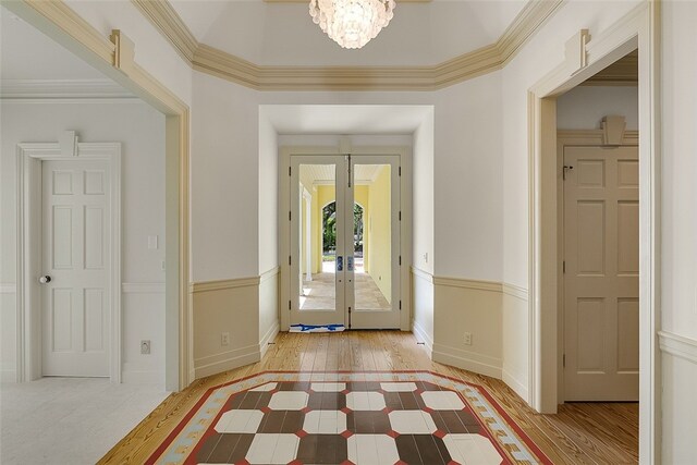 entryway featuring a notable chandelier, light wood-type flooring, french doors, and ornamental molding