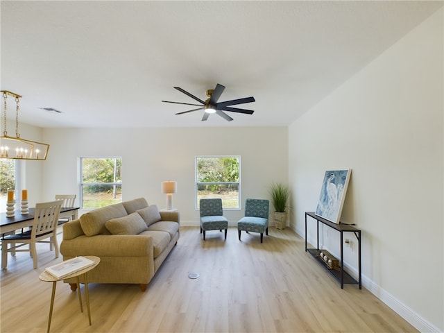 living room featuring ceiling fan with notable chandelier, light hardwood / wood-style floors, and a healthy amount of sunlight