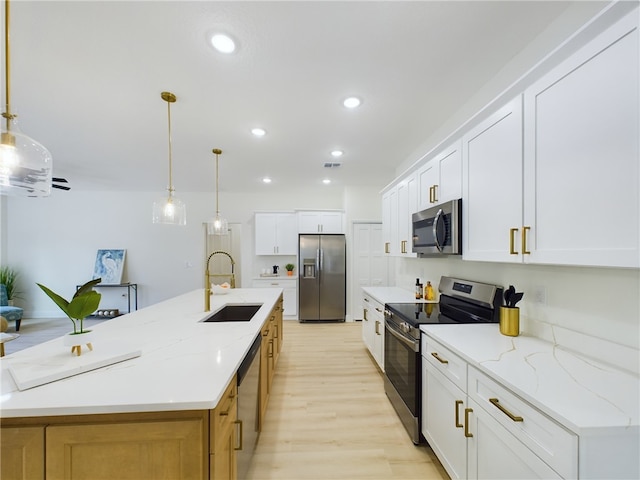 kitchen featuring white cabinetry, sink, stainless steel appliances, and a large island with sink