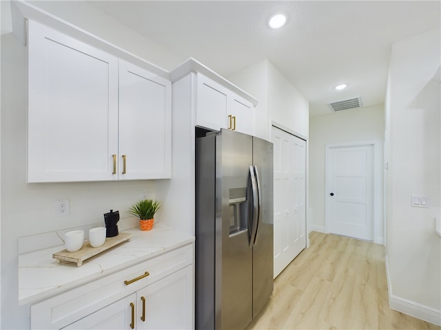 kitchen featuring white cabinetry, light stone countertops, stainless steel fridge, and light hardwood / wood-style flooring