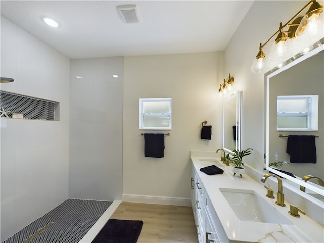 bathroom with tiled shower, vanity, and wood-type flooring