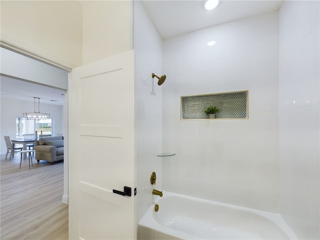 bathroom featuring tiled shower / bath combo, hardwood / wood-style floors, and a notable chandelier