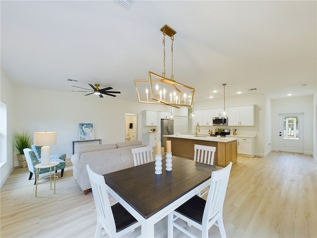 dining space featuring sink, ceiling fan, and light wood-type flooring