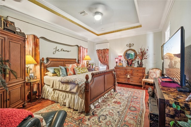 bedroom featuring a tray ceiling, hardwood / wood-style floors, ceiling fan, and crown molding