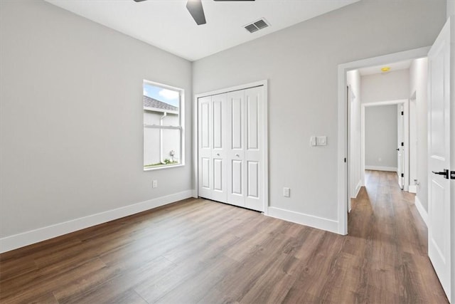 unfurnished bedroom with ceiling fan, wood-type flooring, and a closet