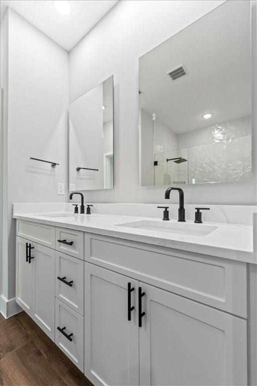 bathroom with hardwood / wood-style floors, vanity, and a shower