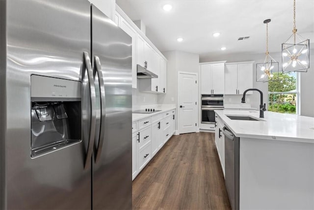 kitchen featuring appliances with stainless steel finishes, dark hardwood / wood-style flooring, sink, white cabinets, and hanging light fixtures