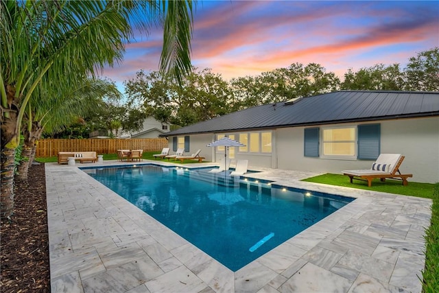 pool at dusk with a patio area