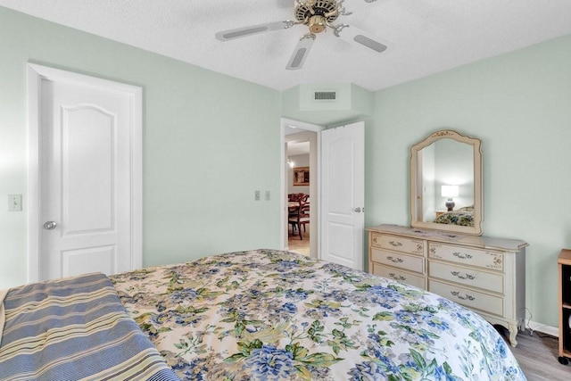 bedroom with wood finished floors, ceiling fan, and visible vents