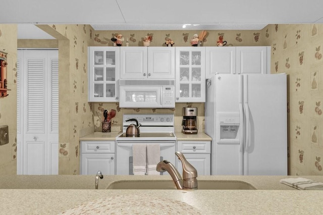 kitchen with light countertops, white appliances, white cabinetry, and wallpapered walls