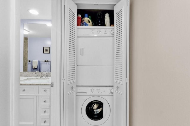 laundry area with a sink, stacked washer / dryer, and laundry area