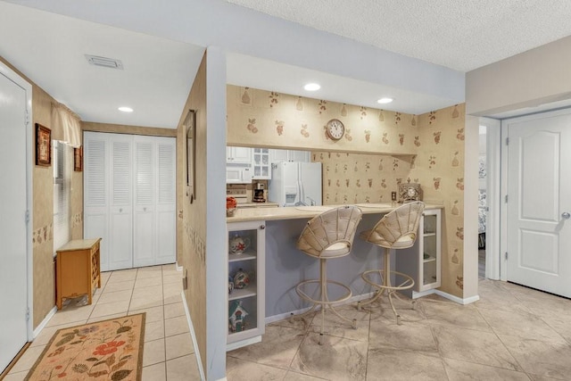 interior space featuring wallpapered walls, baseboards, white appliances, and visible vents