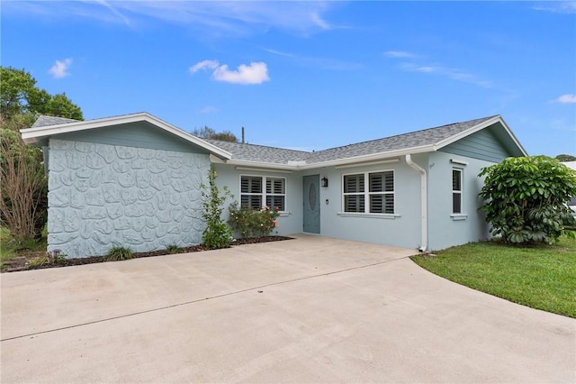 single story home with driveway, stucco siding, roof with shingles, and a front yard