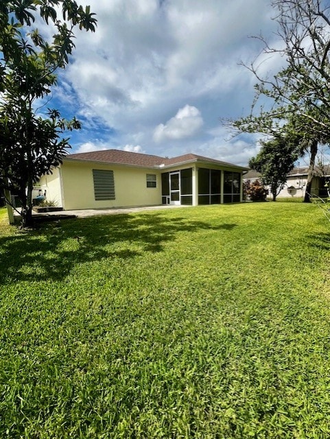 8036 105th Ct, Vero Beach, FL 32967 - rear view of house featuring a sunroom, a yard, and stucco siding