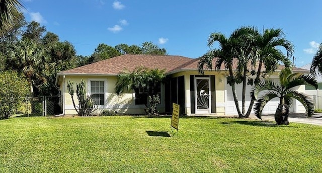 view of front of house with a front yard, a gate, fence, and stucco siding