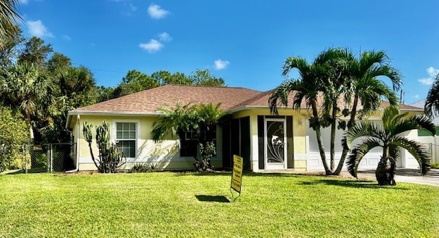 ranch-style home with a front lawn, fence, and stucco siding