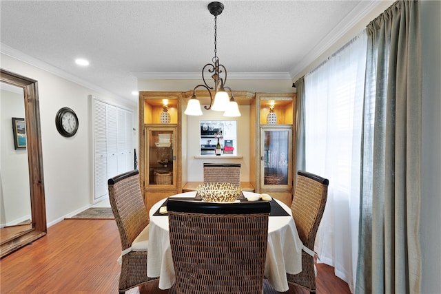 dining room featuring hardwood / wood-style floors, a textured ceiling, ornamental molding, and a notable chandelier