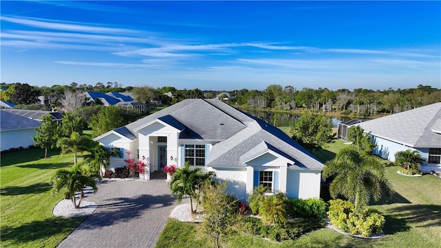 view of front of house featuring decorative driveway, roof with shingles, a front lawn, and stucco siding