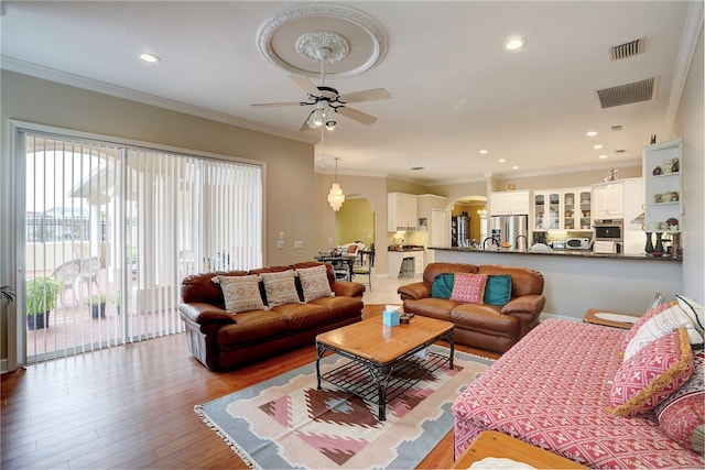 living room with light hardwood / wood-style floors, ceiling fan, and ornamental molding