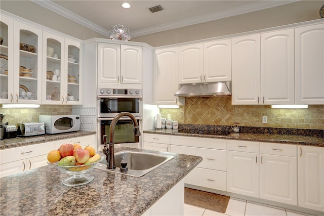 kitchen with dark stone counters, light tile patterned floors, crown molding, white cabinets, and black electric stovetop