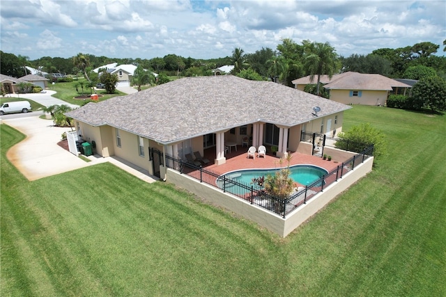 rear view of property featuring a fenced in pool, a yard, and a patio area