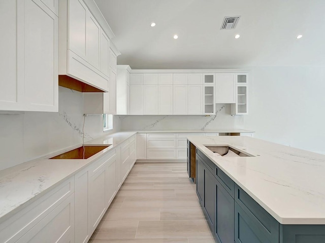 985 Clipper Rd, Vero Beach, FL 32963 - kitchen featuring white cabinets, light stone counters, glass insert cabinets, recessed lighting, and light wood finished floors