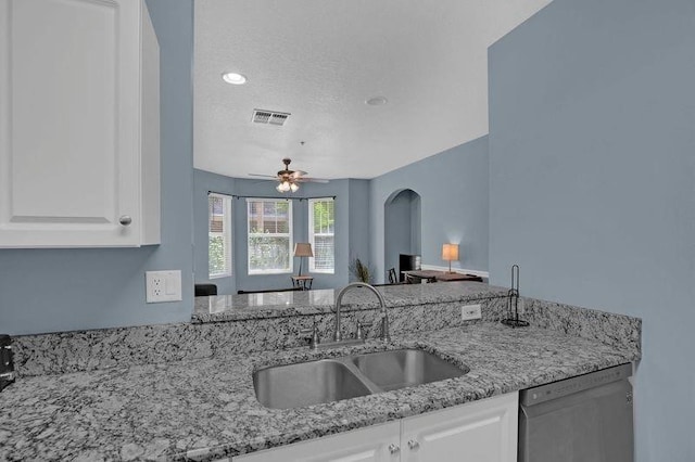 kitchen featuring light stone countertops, sink, white cabinets, stainless steel dishwasher, and ceiling fan