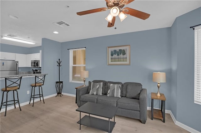 living room featuring ceiling fan, a healthy amount of sunlight, and light hardwood / wood-style floors