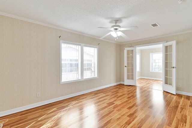 spare room with light hardwood / wood-style floors, ceiling fan, french doors, a textured ceiling, and ornamental molding