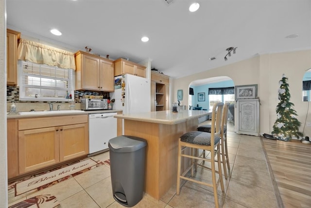 kitchen featuring light brown cabinetry, a center island, white dishwasher, and light hardwood / wood-style floors