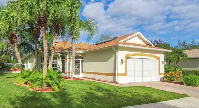 view of front facade featuring solar panels, a front lawn, and a garage