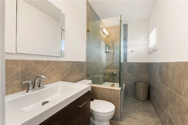 full bathroom with tiled shower / bath, tile walls, toilet, tile patterned floors, and vanity