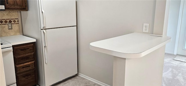 kitchen with light carpet, a peninsula, white appliances, light countertops, and backsplash