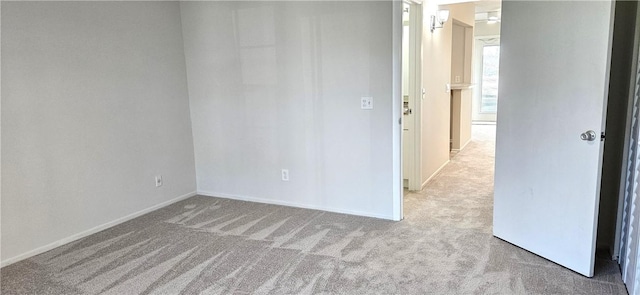 spare room with light carpet and baseboards