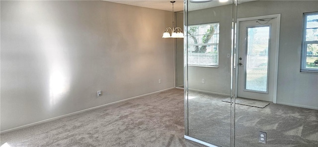 doorway to outside featuring an inviting chandelier, baseboards, and carpet flooring