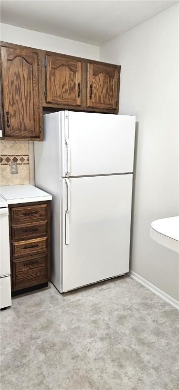 kitchen with stove, baseboards, light countertops, freestanding refrigerator, and tasteful backsplash