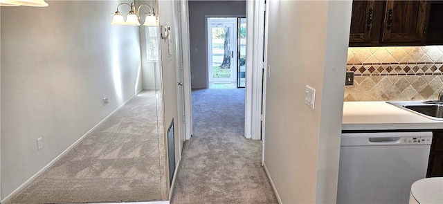 interior space with light carpet, a sink, a notable chandelier, and baseboards