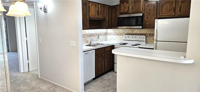 kitchen with light countertops, hanging light fixtures, backsplash, a sink, and white appliances