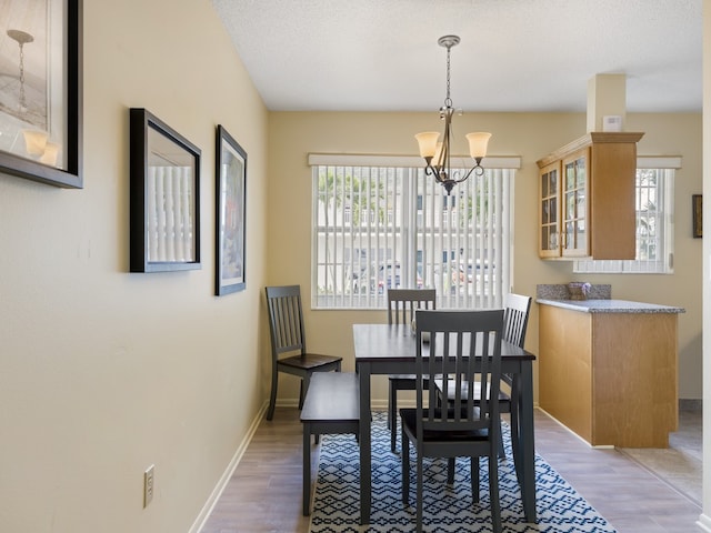 dining area featuring hardwood / wood-style floors, a textured ceiling, and a chandelier